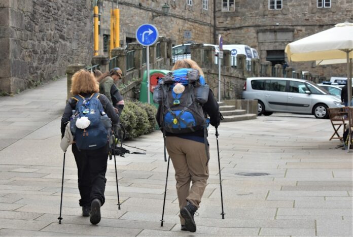 a couple of people walking on a sidewalk with crutches